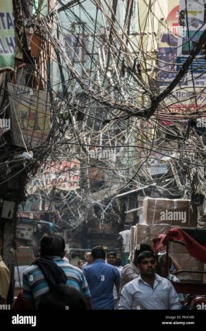 pedestrians-walking-in-narrow-street-with-large-tangled-birds-nest-of-power-cables-overhead-in...jpg